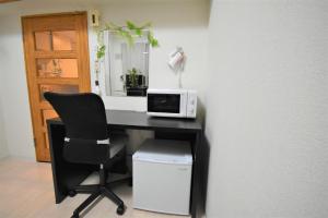 a desk with a microwave and a chair in a room at Tresor Misono - Vacation STAY 9333 in Toyohira