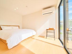 une chambre blanche avec un lit et une fenêtre dans l'établissement Rakuten STAY HOUSE x WILL STYLE Miyazaki Aoshima 101, à Miyazaki