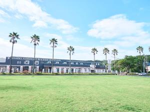 un bâtiment avec des palmiers en face d'un champ dans l'établissement Rakuten STAY HOUSE x WILL STYLE Miyazaki Aoshima 101, à Miyazaki