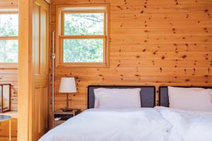 a bed in a room with wooden walls and windows at Relaxing Log Cabin IZU HOUSE- Vacation STAY 85769 in Ito