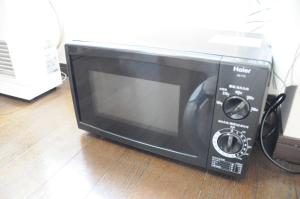 a black microwave sitting on a wooden floor at Ark City Asahikawa - Vacation STAY 8530 in Asahikawa