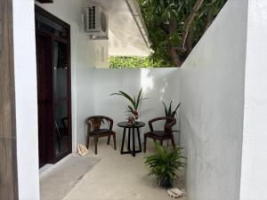 a patio with two chairs and a table with plants at Luk inn at huraa in Huraa
