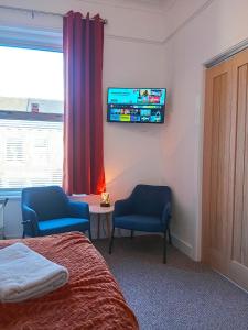 a bedroom with two chairs and a tv on the wall at Double Ensuite 15 mins walk from station in Carlisle