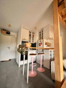 una cucina con sgabelli rosa in una piccola stanza di Appartement calme proche plage a Lanton