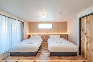 two beds in a room with a window at Apartment Hotel 11 Villa Hanazonocho in Osaka