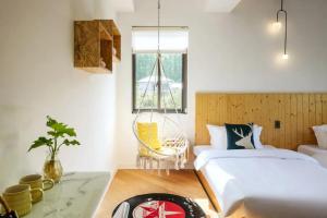 a bedroom with a bed and a chair and a window at Moganshan Moshe Yujia River Tracing Family Pool Bed and Breakfast  +4 photos