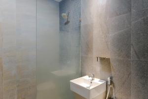 a bathroom with a white sink and a shower at Mono Coliving Kota Tua, Jakarta in Jakarta