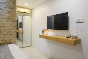 a bedroom with a television on a wall at Mono Coliving Kota Tua, Jakarta in Jakarta