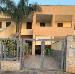 a gate in front of a building with a palm tree at CASA VACANZA Torre Lapillo PREMIUM in Torre Lapillo