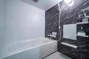 a bathroom with a white tub and a black wall at Mks 201 in Asahikawa