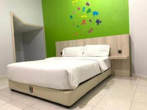 a bedroom with a large bed with a green wall at OYO 89777 Urbanstay Kuantan in Kampong Bukit Ubi