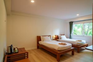 een slaapkamer met twee bedden en een raam bij Mata Pavilion in Loei