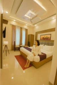 Una mujer sentada en una cama en una habitación de hotel. en Hotel Woodlark !! Affordable luxury stay in Chandigarh Tricity ! Tourist Choice, en Chandīgarh