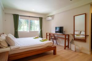 een slaapkamer met een bed, een spiegel en een raam bij Mata Pavilion in Loei