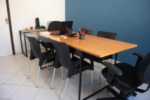 a wooden table with black chairs and a laptop on it at Hotel do Baú in Santa Rosa de Viterbo