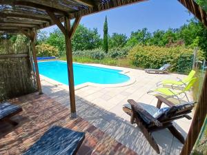 a patio with a swimming pool and two chairs at Gite le sabatou - la grange de cezac in Cézac