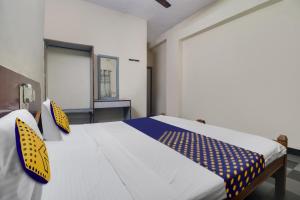 a bedroom with a large white bed with yellow and blue pillows at SPOT ON New Balaji Residency in Hyderabad +19 photos