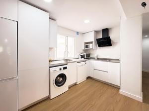 una cocina con gabinetes blancos y una lavadora y secadora en Apartamento La Caleta Grupo AC Gestion, en Cádiz