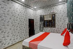 a bedroom with a bed and a wall with wallpaper at Hotel O New Jagrani palace in Kānpur