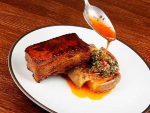 a white plate with a piece of meat and a spoon at The Cookbook Gastro Boutique Hotel & SPA in Calpe