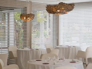 a dining room with white tables and chairs and windows at The Cookbook Gastro Boutique Hotel & SPA in Calpe