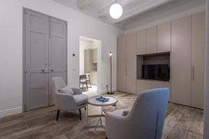 a living room with two chairs and a tv at Old Theatre Suites - Panarea in Valletta