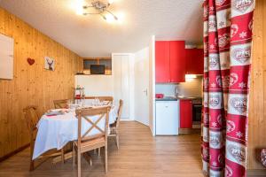 a dining room with a table and a kitchen with red cabinets at Joli Appt 2 Centre Village Valloire in Valloire +13 photos