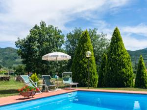 a swimming pool with two chairs and an umbrella at Farmhouse in Tuscany with Panoramic Pool in Castiglion Fiorentino