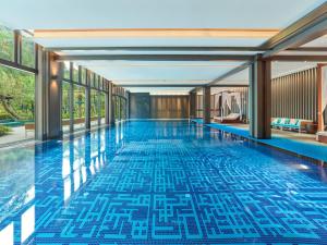 Liutangにある桂林雁山宋品酒店 Song Hotel Guilinの青いタイルの床と窓が備わるスイミングプール
