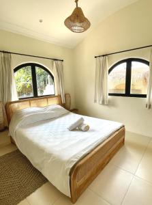 a bedroom with a large bed with two windows at Large Private 2BR Villa with Playground and Jacuzzi near Pererenan in Dalung