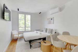 a white living room with a couch and a table at Appartement moderne et tout équipé in La Plaine-Saint-Denis