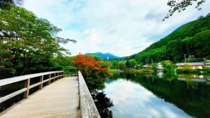 un pont en bois sur une rivière à côté d'une montagne dans l'établissement KOTONONE MAI - Vacation STAY 87621, à Yufu