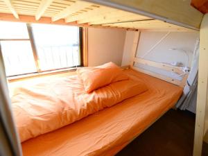 ein orangefarbenes Bett in einem kleinen Zimmer mit Fenster in der Unterkunft Kochi - House - Vacation STAY 96172 in Kōchi