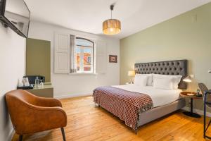 a bedroom with a bed and a chair at Casa do Bairro by Shiadu in Lisbon