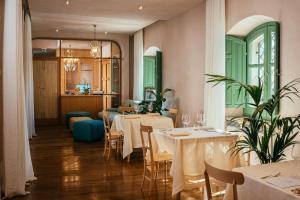 a restaurant with white tables and chairs and green doors at Casa di Nonno in Serdiana