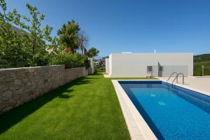 a swimming pool with green grass next to a house at Theologos Residencies in Theologos