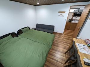 a bedroom with a green bed and a couch at guest house Ki-zu - Vacation STAY 94978v in Nishio