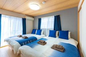 Dos camas en una habitación con azul y blanco. en ASAHI HOUSE 2nd floor - Vacation STAY 92770, en Naha
