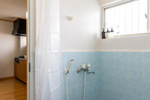 a bathroom with a shower with blue tiles and a window at ASAHI HOUSE 2nd floor - Vacation STAY 92921 in Naha +24 photos