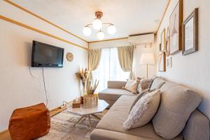 a living room with a couch and a tv at ASAHI HOUSE 2nd floor - Vacation STAY 92921 in Naha