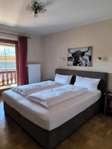 a large bed in a bedroom with a cow picture on the wall at Haus Blindauer Eck in Reit im Winkl