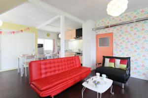 a living room with a red couch and a table at Sun River Annex Inaho - Vacation STAY 95961 in Kita-hamachō