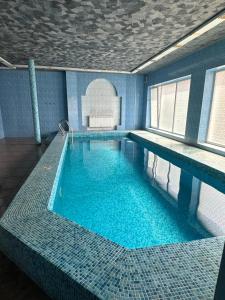 a large swimming pool in a room with blue tiles at Koral Hotel in Verkhniy Koropets