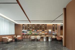 Atour Hotel Hohhot Hailiang Plaza Zhongshan Road Subway Station في هوهوت: مكتبة فيها طاولة وكراسي ورفوف كتب