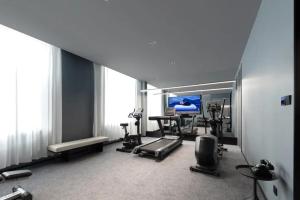 Atour Hotel Hohhot Hailiang Plaza Zhongshan Road Subway Station في هوهوت: غرفة بها صالة رياضية مزودة بتلفزيون ومعدات رياضية
