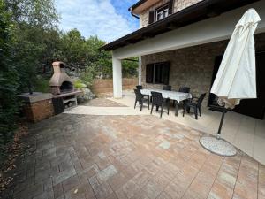 a patio with a table and chairs and a fireplace at Villa ISA 4 bedrooms, 4 bathrooms, sauna, jacuzzi, panoramic view in Vrh