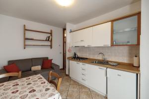 a kitchen with white cabinets and a couch in a room at Dolomitihouse CASTAGNER in Fiera di Primiero