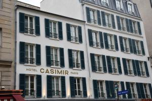 パリにあるHôtel Casimirの緑のシャッターが付いた白い大きな建物