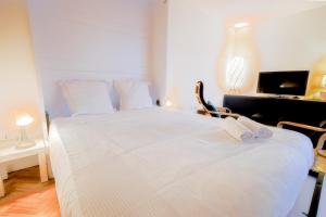 1 dormitorio con 1 cama blanca, escritorio y TV en Le Saint-Sulpice - Résidence calme, terrasse, en Issy-les-Moulineaux