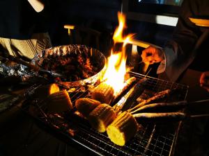 a man cooking food on a grill with a fire at Nasusanso - Vacation STAY 9643 in Nasu-yumoto